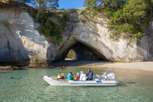 a group of people in a boat in front of a cave at Hahei Retreat in Hahei