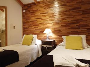 2 camas en una habitación con pared de madera en Hostal Fernando de Magalhaes, en Punta Arenas