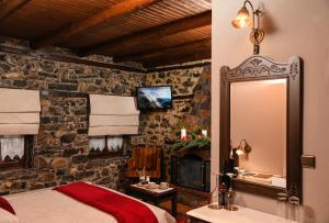 a bedroom with a bed and a mirror and a fireplace at Archontiko Tarsouna in Palaios Agios Athanasios