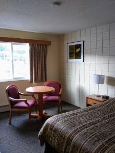 a hotel room with a table and chairs and a bed at Haida Way Motor Inn in Port McNeill