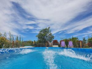 una piscina con 2 sillas moradas. en Rincón del Alma en Saladillo