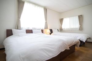 2 bedden in een slaapkamer met witte lakens bij RIVERSIDE INN KAMAKURA in Kamakura