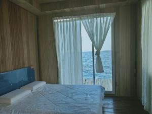 een slaapkamer met een groot raam met uitzicht op de oceaan bij Egang-egang Resort Bum-Bum Island Semporna in Semporna