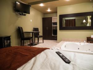 a bedroom with a tub and a table with chairs at Motel Classique in Joliette