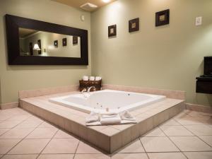 a bath tub in a bathroom with a large mirror at Motel Classique in Joliette