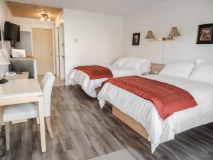a hotel room with two beds and a desk and a table at Motel Classique in Joliette