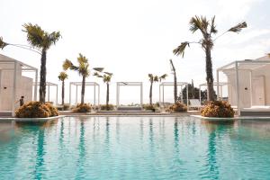 a swimming pool with palm trees in the background at Art Deco Luxury Hotel & Residence in Bandung