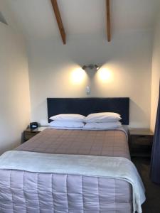 a bedroom with a large bed with two pillows at Bay Cabinz Motel in Paihia