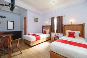 een hotelkamer met twee bedden en een stoel bij RedDoorz at Sedayu 1 Parapat in Parapat