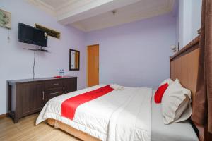 um quarto com uma cama e uma televisão na parede em RedDoorz @ Parapat em Parapat