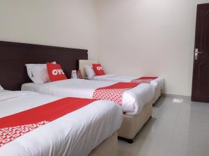 drie bedden in een kamer met rode en witte kussens bij Super OYO 107 Al Areen Hotel Apartments in Shāhiq