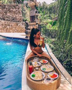 een vrouw in een dienblad met eten naast een zwembad bij Sweet Escape in Sidemen