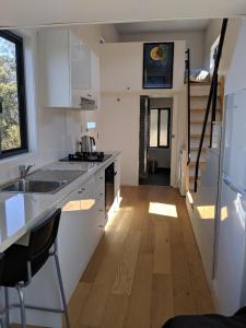 a kitchen with white cabinets and a wooden floor at Bottletree Gardens - Mini Manson Blue in Gold Coast