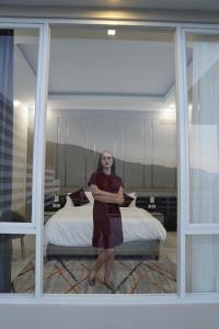 kobieta stojąca przed sypialnią z łóżkiem w obiekcie Nirvana Villas Puncak w mieście Puncak