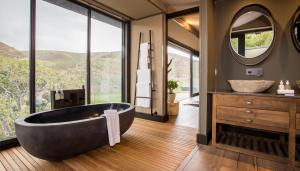 
a bathroom with a large tub and a large window at Botlierskop Private Game Reserve in Reebok
