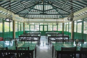 un restaurante con mesas verdes, sillas y ventanas en SUPER OYO 1959 Penginapan Kepurun Pawana Indonesia, en Sleman