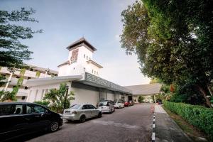 ein weißes Gebäude mit Autos auf einem Parkplatz in der Unterkunft Tunamaya Beach & Spa Resort- Desaru in Desaru