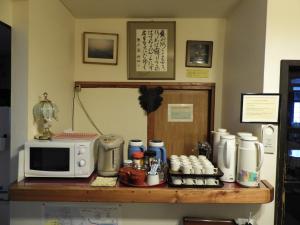 a counter top with a microwave and a coffee maker at Brocken Hutte in Hakuba