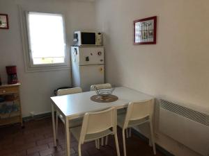 a kitchen with a white table and chairs and a refrigerator at Charmante maison au coeur de la pinède Classée 3 étoiles in Lacanau