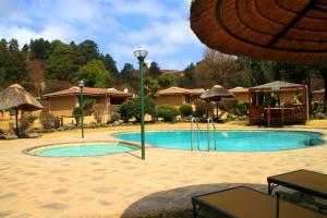 a swimming pool in a resort with an umbrella at Gooderson Leisure Riverbend Chalets Self Catering and Timeshare Gold Crown Resort in Drakensberg Garden