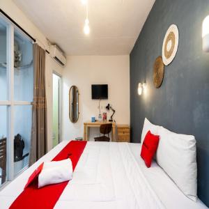 ein Schlafzimmer mit einem großen weißen Bett mit roten Kissen in der Unterkunft RedDoorz near Exit Toll Tanah Baru Bogor in Bogor