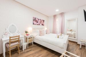 a white bedroom with a bed and a desk and a mirror at Apartment Sol Gran Vía in Madrid