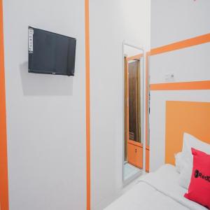 a room with a bed with a mirror and a tv at RedDoorz @ Jalan Sukabangun 2 Palembang in Palembang