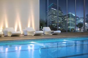 a group of white chairs sitting next to a swimming pool at Lotte Hotel Seoul Executive Tower in Seoul