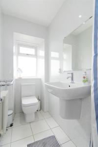 a white bathroom with a sink and a toilet at Beach House No1 With Amazing Sea Views And Direct Beach Access in Fairlie