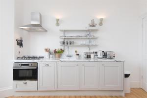 a kitchen with white cabinets and a stove at Beach House No1 With Amazing Sea Views And Direct Beach Access in Fairlie