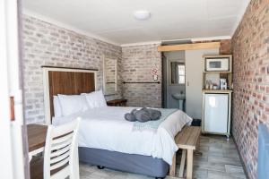 a bedroom with a bed and a brick wall at Opstal Guestfarm in Potchefstroom
