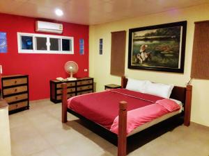 sypialnia z łóżkiem i czerwoną ścianą w obiekcie LLamados Fishing Lake w mieście San Kamphaeng
