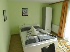 a bedroom with a white bed with green walls at Alpenappartement Claudia in Piesendorf