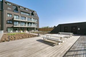 a row of wooden benches in front of a building at Belcasa Family Suites & Lofts in Westende