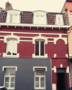 a large red brick building with white windows at La maisonnette au centre ville in Lens