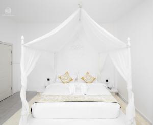 a white bedroom with a white canopy bed at SYRI Boutique Guesthouse Restaurant & Cafe in Vientiane