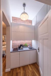 a kitchen with white cabinets and a brick wall at JP Sopot Apartamenty in Sopot