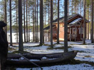 eine Hütte im Wald mit einem Boot im Schnee in der Unterkunft Rokuan Unelma in Rokua