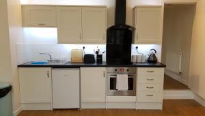 a kitchen with white cabinets and a stove top oven at Number 1, Beech Road in Manchester