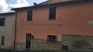 a pink building with windows and a stone wall at Casetta nel centro di Sorgono in Sorgono