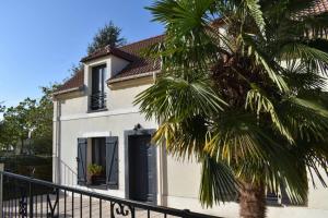 a white house with a palm tree in front of it at Lorely - Maison proche Disneyland et Paris in Montévrain