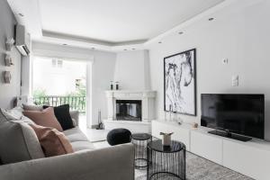 a white living room with a couch and a tv at Modernized & Spacious 2BD Apartment in Chalandri by UPSTREET in Athens