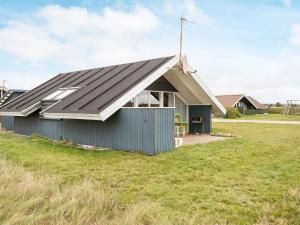 una casa con techo de metal en la parte superior de un campo en 5 person holiday home in Harbo re en Harboør