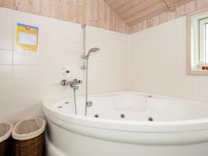 a white bath tub in a white tiled bathroom at 8 person holiday home in Harbo re in Harboør