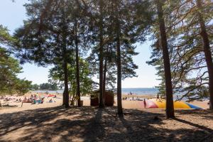 una playa con árboles y gente en la playa en Karlstad Swecamp Bomstadbaden, en Karlstad