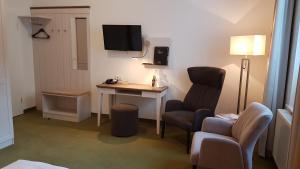 a room with a desk and two chairs and a television at Ringhotel Villa Margarete in Waren