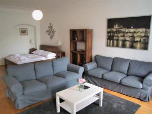 a living room with two blue couches and a bed at Charles Bridge Apartments in Prague