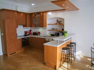 a kitchen with wooden cabinets and a counter with bar stools at Charles Bridge Apartments in Prague