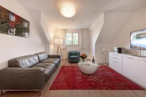 a living room with a couch and a red rug at Mintrops Stadt Hotel Margarethenhöhe in Essen