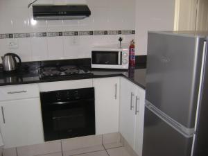 a kitchen with a stove and a microwave and a refrigerator at North Beach Durban Apartments in Durban